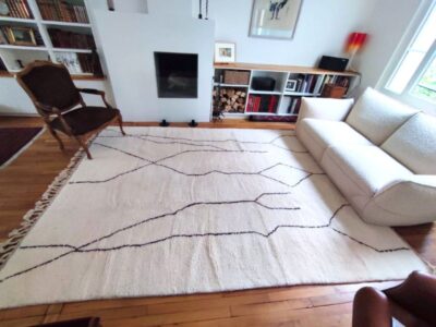 Grand tapis Beni Ouarain aux lignes noires mêlant fauteuil ancien et canapé contemporain
