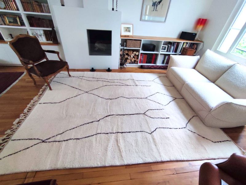 Grand tapis Beni Ouarain aux lignes noires mêlant fauteuil ancien et canapé contemporain