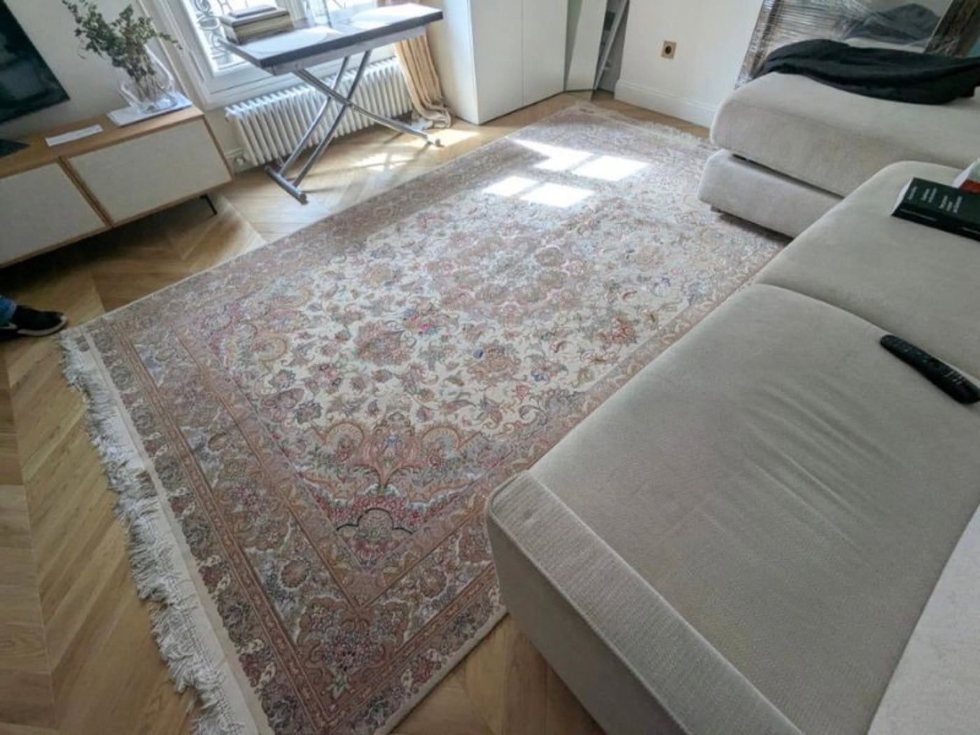 Tapis persan Tabriz en laine et soie à fond ivoire dans un salon parisien au parquet point de Hongrie