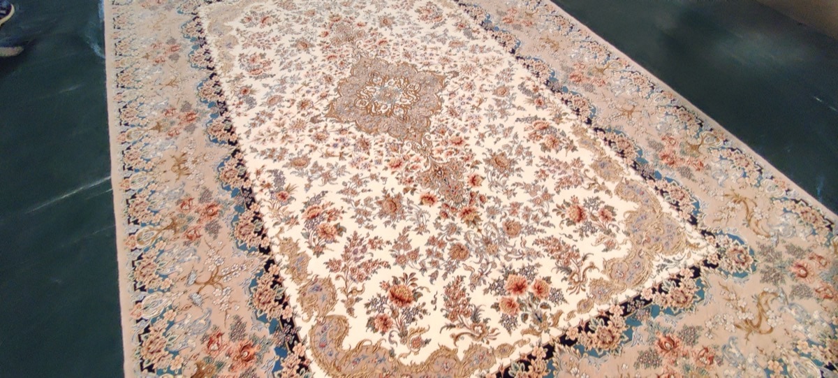 Tapis Ispahan à médaillon floral central sur fond ivoire, bordure marine et fleurs corail, collection Tapis Bouznah